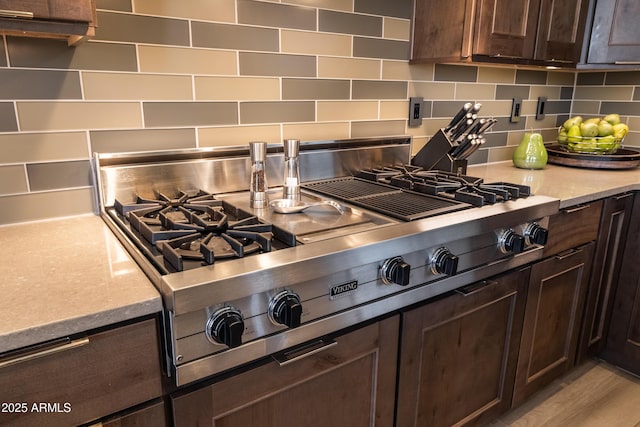 kitchen featuring light stone counters, dark brown cabinets, backsplash, and stainless steel gas cooktop