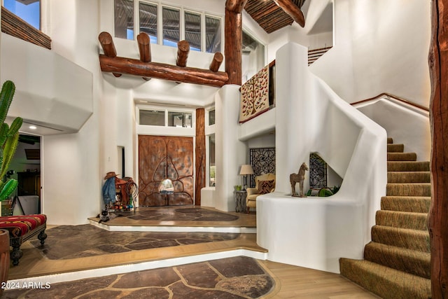 foyer featuring a towering ceiling, wood-type flooring, and plenty of natural light