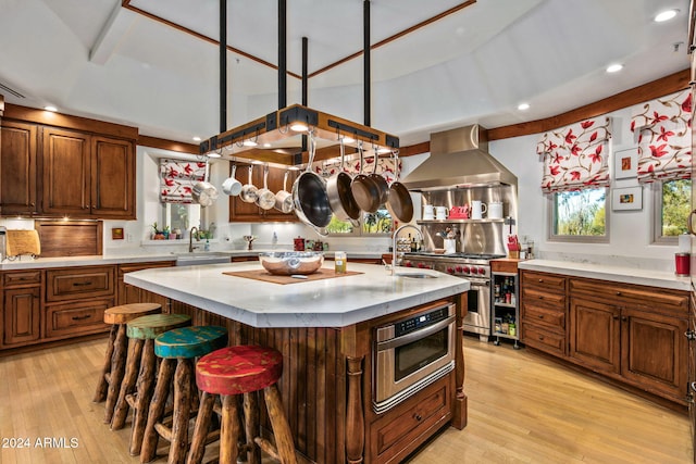 kitchen featuring a center island with sink, sink, ventilation hood, and light hardwood / wood-style flooring