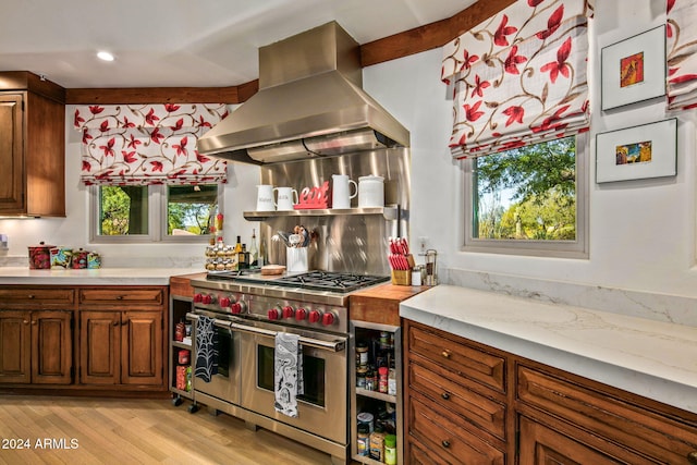 kitchen featuring range with two ovens, a wealth of natural light, light wood-type flooring, and island range hood