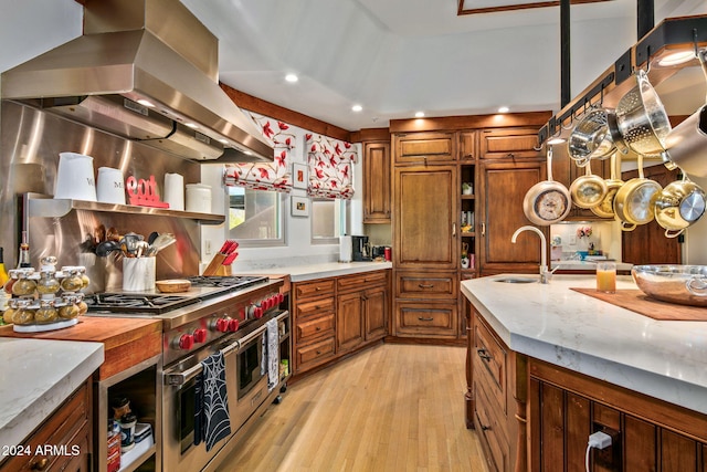 kitchen with sink, light hardwood / wood-style floors, decorative light fixtures, exhaust hood, and double oven range