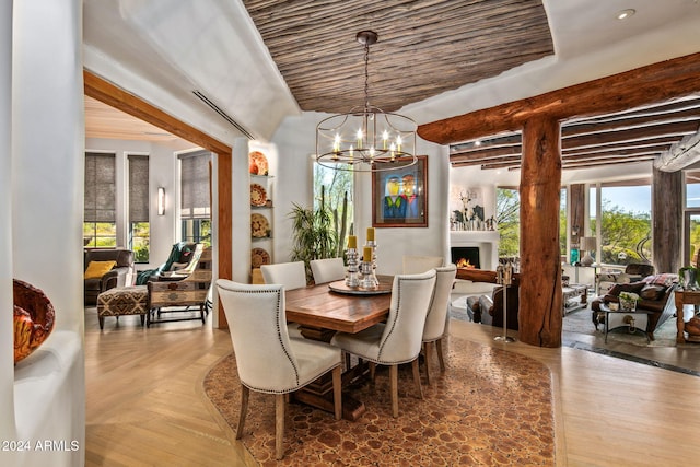 dining space featuring beamed ceiling, a wealth of natural light, and an inviting chandelier