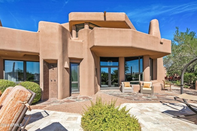 back of house with an outdoor living space and a patio