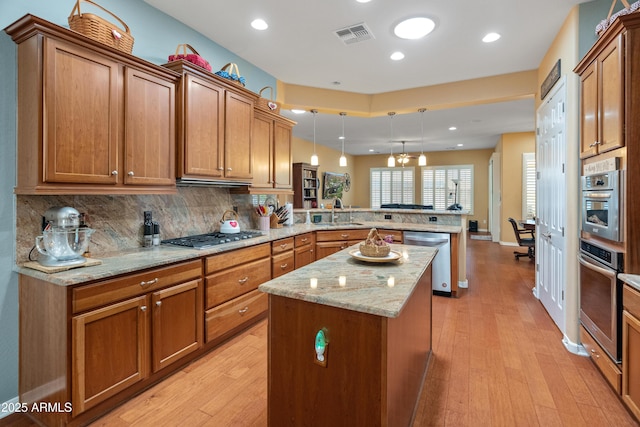 20506 N 271st Ave, Buckeye, AZ 85396 - kitchen with brown cabinetry, a center island, light wood finished floors, a peninsula, and stainless steel appliances
