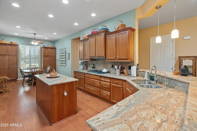 20506 N 271st Ave, Buckeye, AZ 85396 - kitchen featuring ceiling fan, light stone countertops, a sink, brown cabinetry, and stainless steel gas stovetop
