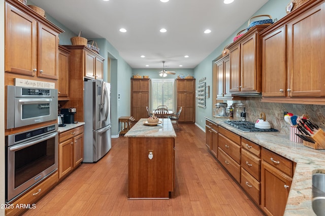 20506 N 271st Ave, Buckeye, AZ 85396 - kitchen featuring a center island, ceiling fan, brown cabinetry, and stainless steel appliances