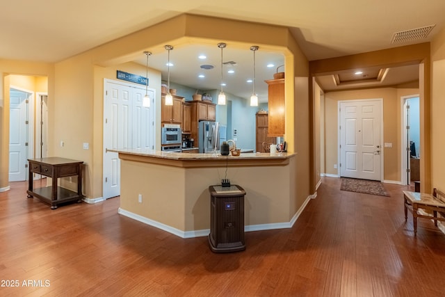 20506 N 271st Ave, Buckeye, AZ 85396 - kitchen with brown cabinets, appliances with stainless steel finishes, decorative light fixtures, visible vents, and dark wood-style floors