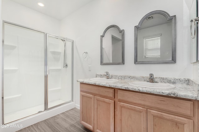 full bathroom featuring double vanity, a sink, and a shower stall