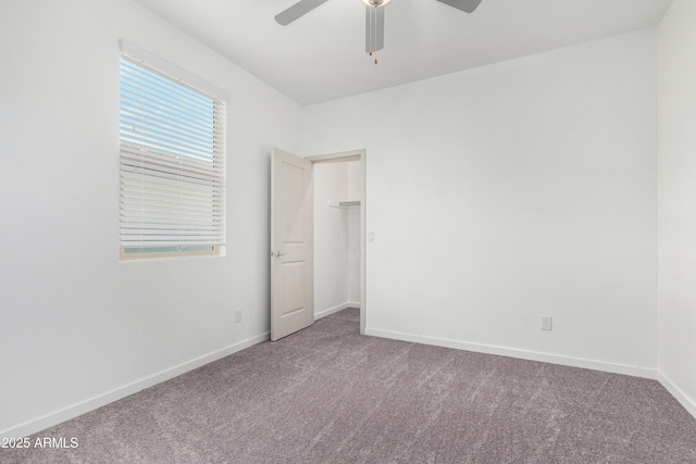 carpeted spare room featuring ceiling fan and baseboards