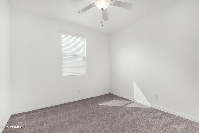 carpeted spare room with a ceiling fan and baseboards