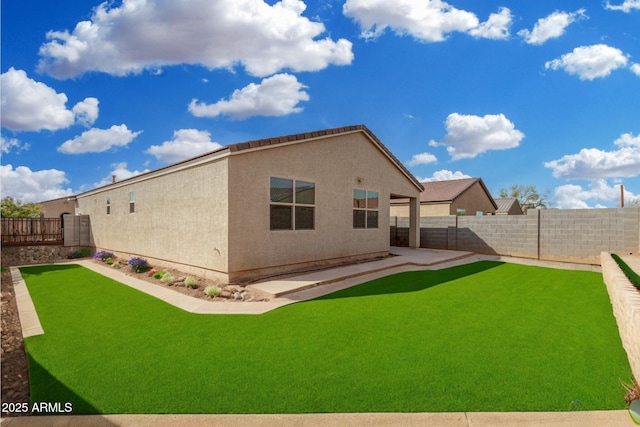 rear view of property featuring a fenced backyard and stucco siding