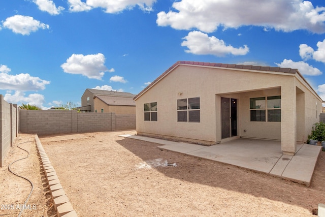 rear view of property with stucco siding, a fenced backyard, and a patio