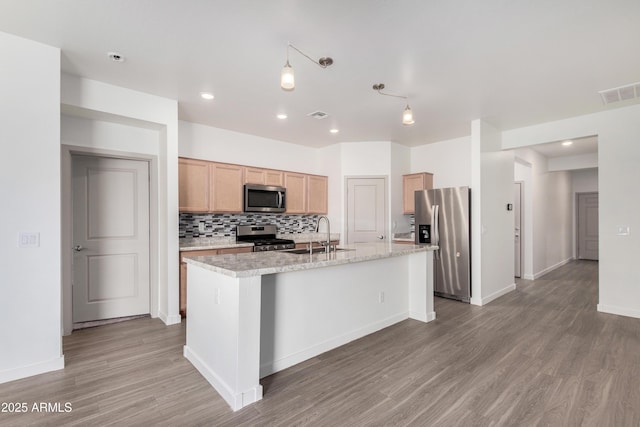 kitchen featuring visible vents, decorative backsplash, stainless steel appliances, light wood-type flooring, and a sink