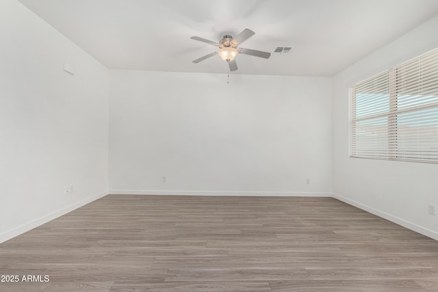 empty room with ceiling fan, baseboards, visible vents, and light wood-style floors