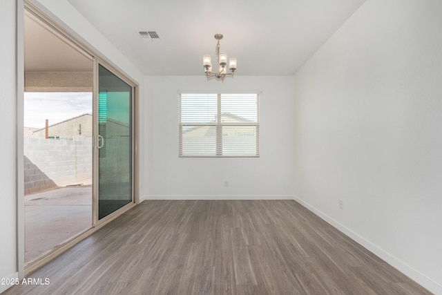 unfurnished room with a chandelier, visible vents, baseboards, and wood finished floors