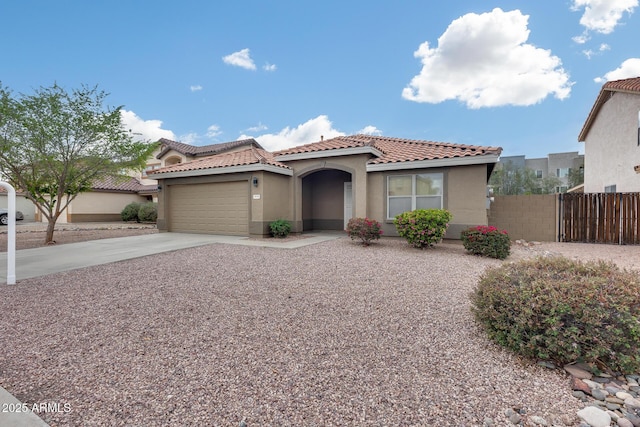 mediterranean / spanish home with stucco siding, driveway, a tile roof, and fence