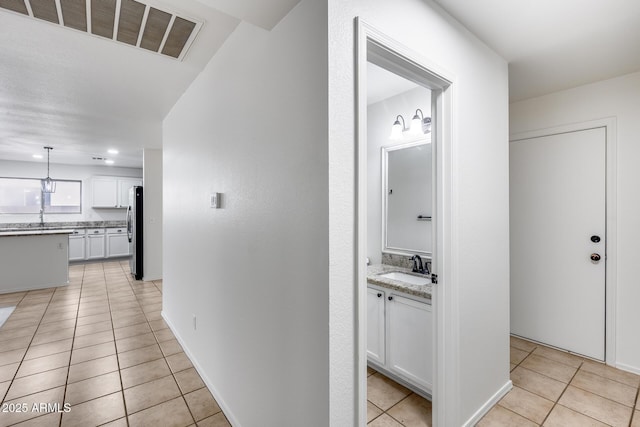 hall with light tile patterned flooring, visible vents, and a sink