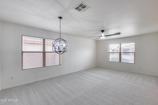 empty room with ceiling fan with notable chandelier, light colored carpet, visible vents, and baseboards