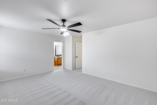 spare room with light colored carpet, baseboards, and ceiling fan