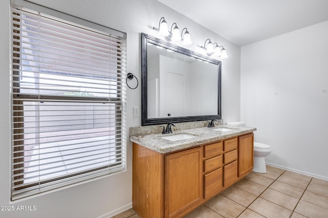 bathroom with a sink, toilet, double vanity, and tile patterned floors