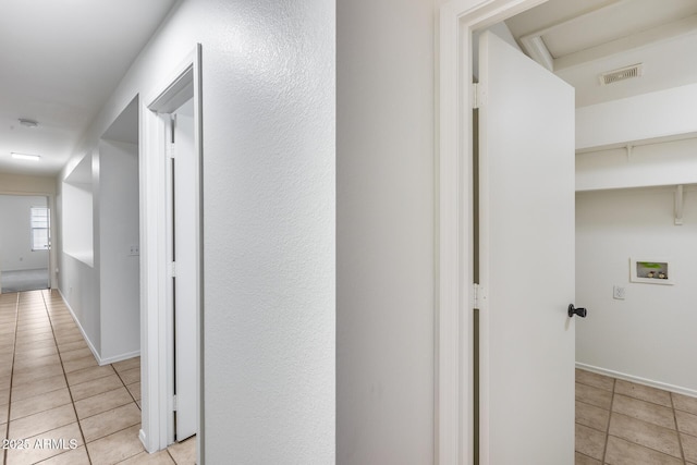 hall with visible vents, baseboards, and tile patterned flooring