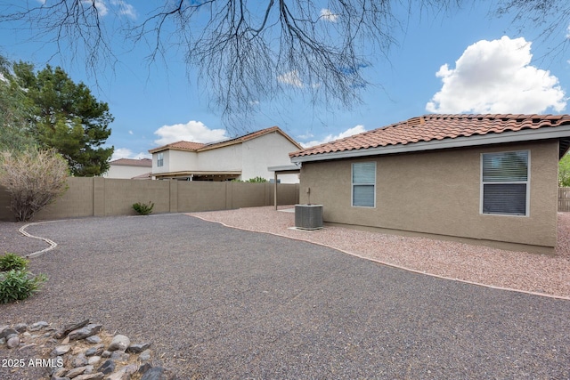 rear view of house featuring central air condition unit, a tile roof, stucco siding, a fenced backyard, and a patio area