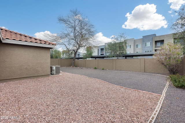 view of yard with central AC unit and fence