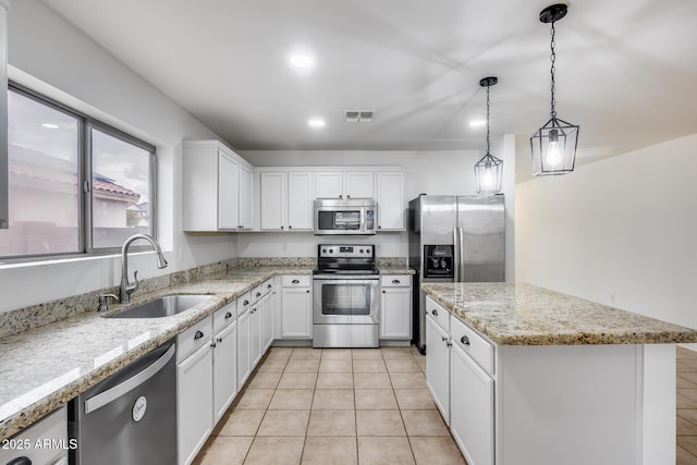 kitchen with visible vents, a center island, stainless steel appliances, white cabinetry, and a sink