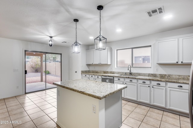 kitchen with visible vents, a center island, dishwasher, light tile patterned floors, and a sink