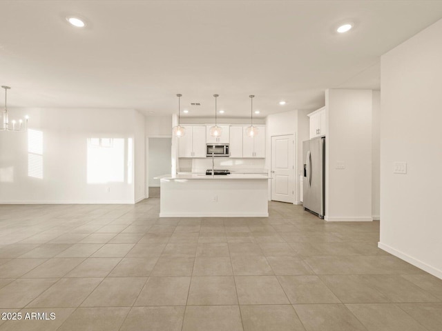 kitchen featuring white cabinetry, a kitchen island with sink, decorative light fixtures, and appliances with stainless steel finishes