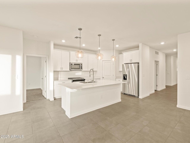 kitchen featuring a center island with sink, white cabinets, sink, hanging light fixtures, and stainless steel appliances