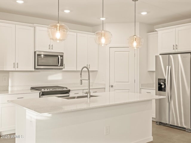 kitchen featuring decorative light fixtures, stainless steel appliances, and an island with sink