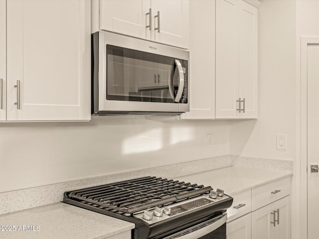 kitchen featuring white cabinets, stainless steel appliances, and light stone counters