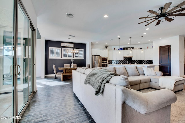 living room featuring light hardwood / wood-style floors and ceiling fan with notable chandelier