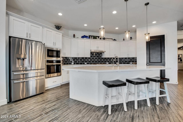 kitchen with light hardwood / wood-style flooring, white cabinets, hanging light fixtures, and appliances with stainless steel finishes