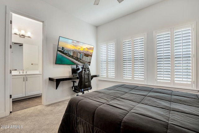 carpeted bedroom with ensuite bathroom, ceiling fan, sink, and multiple windows