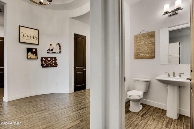 bathroom with toilet, wood-type flooring, and sink