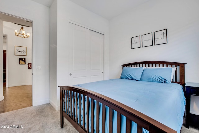 bedroom with a chandelier, light colored carpet, and a closet