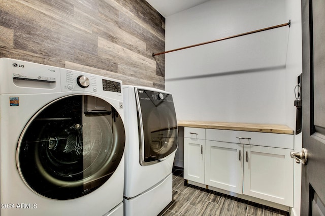 washroom featuring wooden walls, dark hardwood / wood-style floors, cabinets, and washing machine and dryer