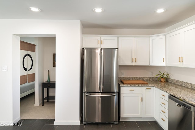 kitchen featuring light stone countertops, white cabinets, stainless steel appliances, and dark carpet