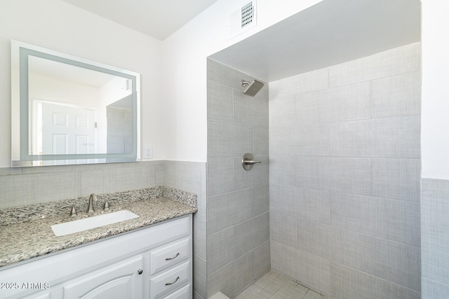 bathroom featuring backsplash, vanity, and tiled shower