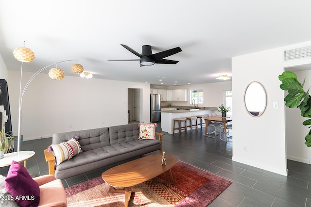 living room with ceiling fan, sink, and dark tile patterned floors