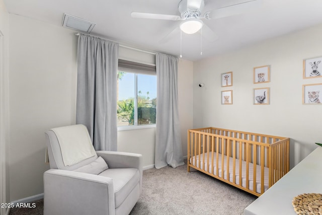 carpeted bedroom featuring a nursery area and ceiling fan