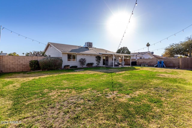 rear view of house with central AC, a patio area, and a lawn