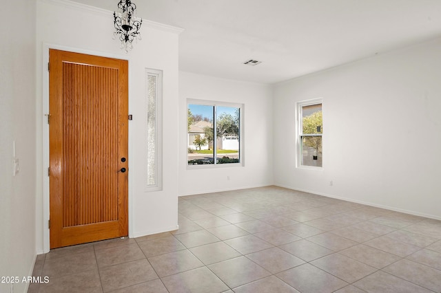 foyer featuring crown molding, a chandelier, and light tile patterned floors