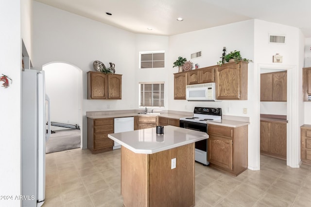 kitchen with a center island, a high ceiling, white appliances, and sink