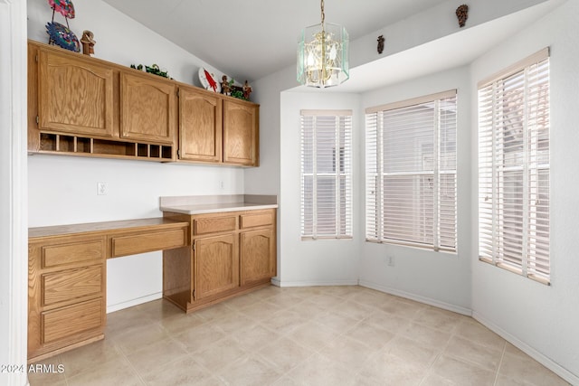 kitchen featuring vaulted ceiling, built in desk, hanging light fixtures, and a chandelier