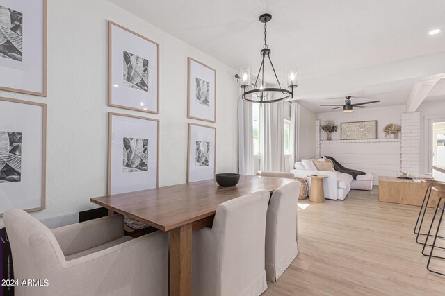 dining space with ceiling fan with notable chandelier, light hardwood / wood-style flooring, and a wealth of natural light