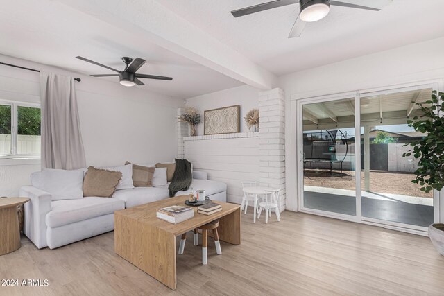 living room featuring beam ceiling, light hardwood / wood-style floors, and ceiling fan