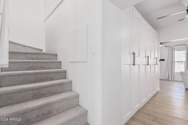 stairway with ceiling fan and hardwood / wood-style flooring